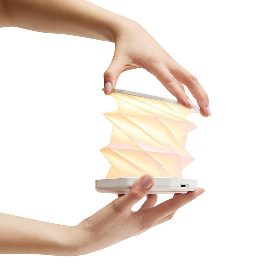 Faltbare weiße LED Tischlampe beim Aufklappen in den Händen